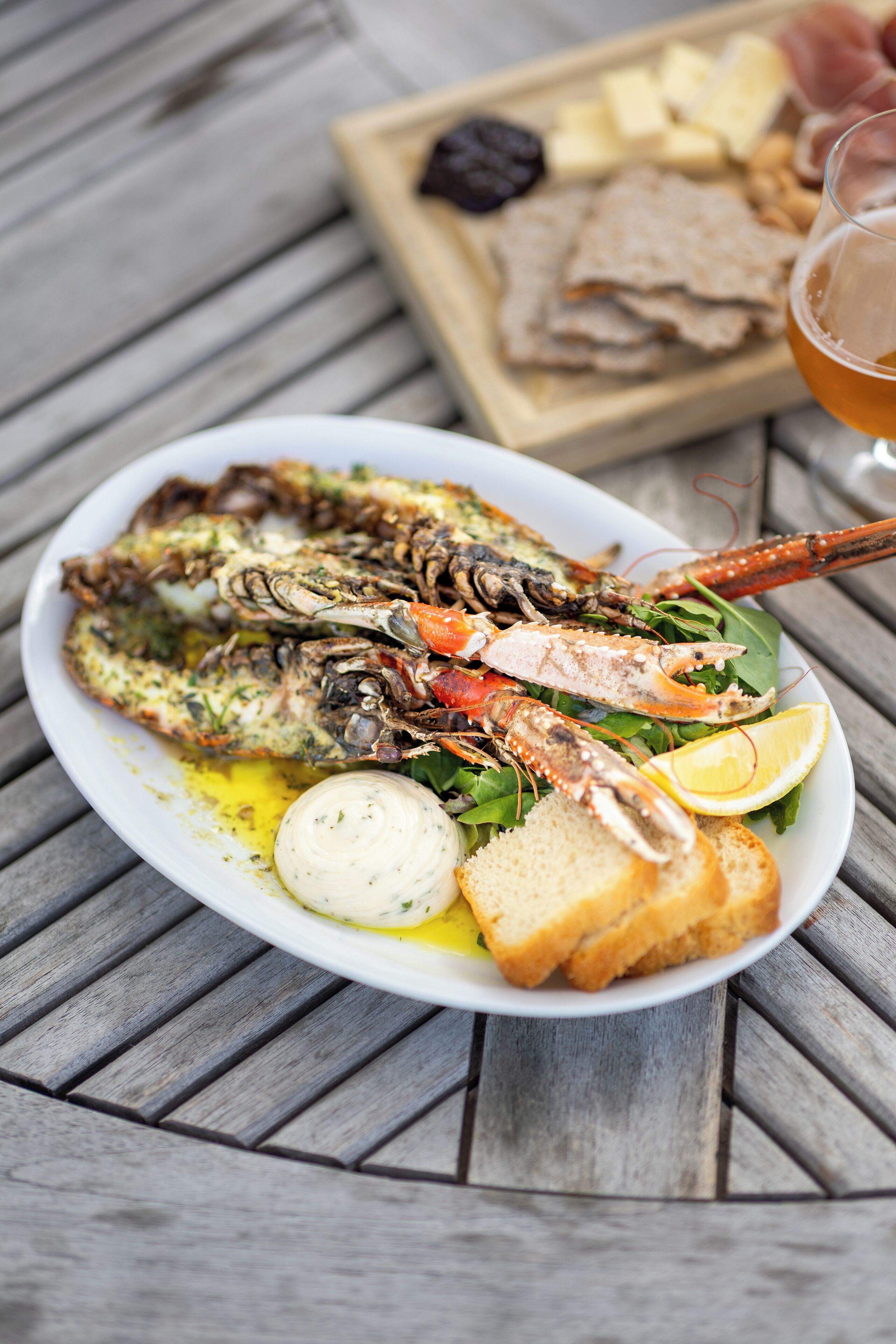 A seafood platter with lobster, bread, and lemon on a wooden table.