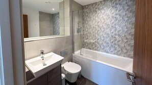 Ein modernes Badezimmer mit Waschbecken, Toilette und Badewanne in Weiß.