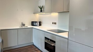 Eine moderne Küche mit weißen Schränken, einer eingebauten Mikrowelle, einem Herd und einem Spülbecken.