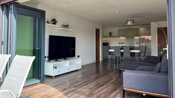 Ein modernes Wohnzimmer mit Flachbildfernseher, einer Couch und einem Essbereich mit Stühlen und Tisch.