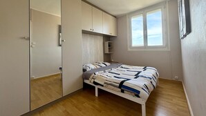 Ein Schlafzimmer mit Bett, Kleiderschrank, Spiegel und Fenster.