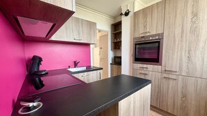 Eine moderne Küche mit schwarzer Arbeitsplatte, Holzschränken und einer rosa Spritzschutzleiste.