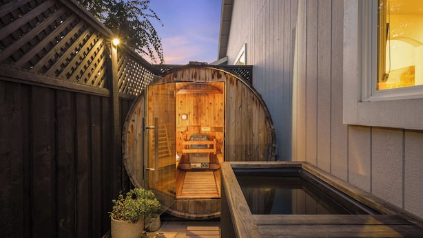 A wooden sauna structure with a bench inside, a small pool, and a potted plant outside. - Wildflower (Windsor)