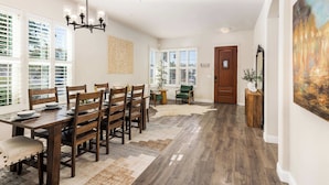 A dining area with a wooden table and chairs, a chandelier, and a large painting on the wall. - Wildflower (Windsor)