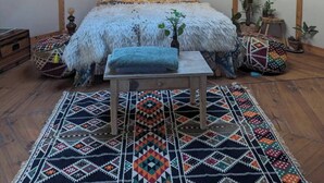 A cozy attic bedroom with a wooden ceiling, a large bed with a fluffy white cover, a small table, and a colorful rug. - Yourte in Provence , at la Mauvaise Herbe, Barjols (Barjols)