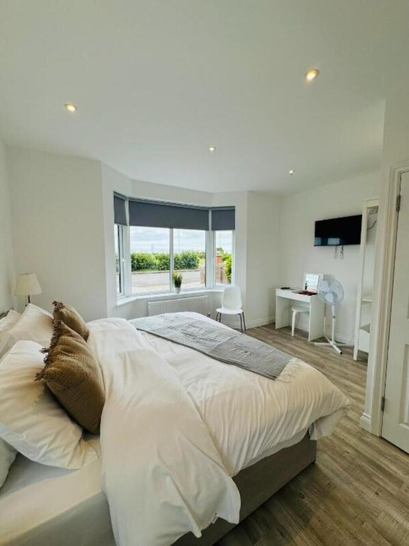 A modern bedroom with a large bed, a desk, and a chair.