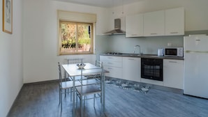 Una cucina moderna con mobili bianchi, piano cottura a gas, forno a microonde ed elettrodomestici inclusi.