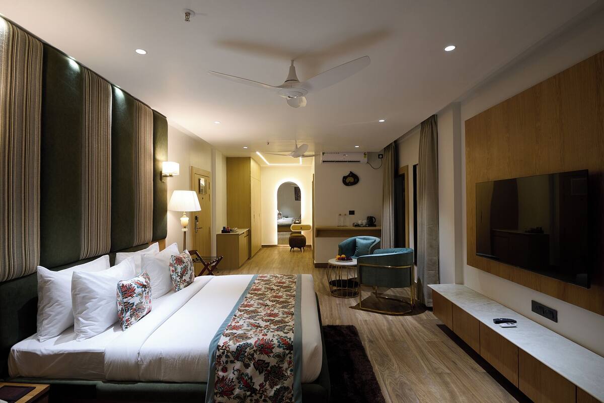 A hotel room with a bed, a TV, a desk, and a chair.