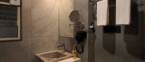 A modern bathroom with a sink, mirror, towel rack, and hairdryer.