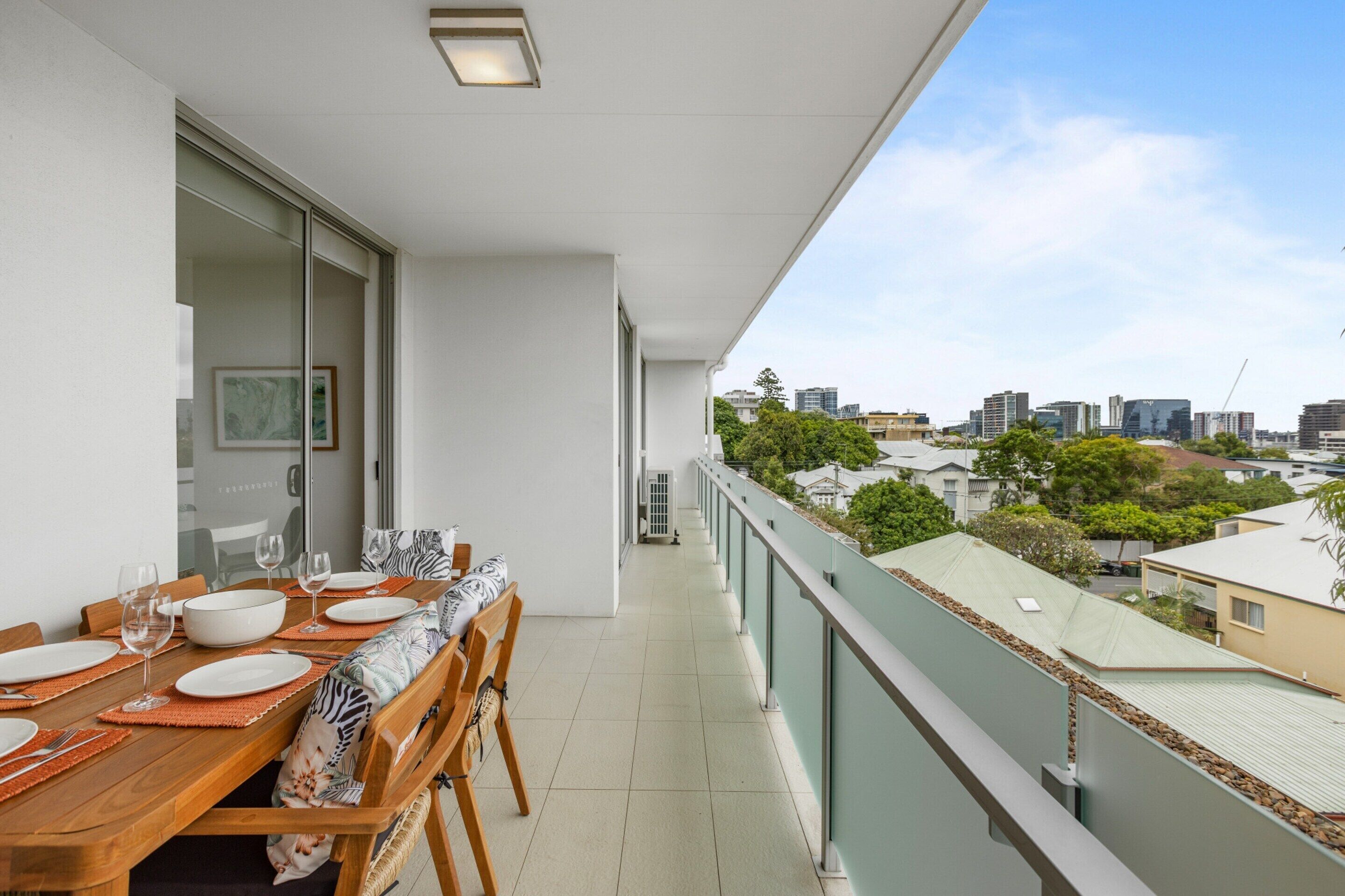 Ein Balkon mit einem Esstisch für vier Personen mit Blick auf die Stadt.