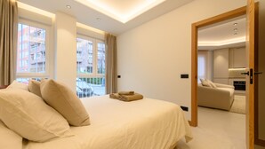 A modern hotel room with a large bed, a view of the city through the window, and a separate living area. - M Scr7b1 Amplio Piso Exterior de un Dormitorio e (Madrid)