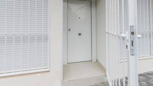 A white door with a small step leading up to it, a metal gate to the right, and a vent above the door. - M Scr7b1 Amplio Piso Exterior de un Dormitorio e (Madrid)