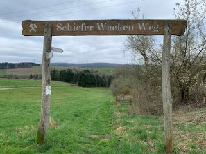 Een houten bordje met de tekst 'Schiefer Wacken Weg' en een pijltje dat de richting aangeeft.