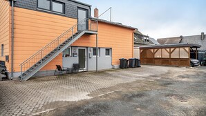 A building with a staircase leading to a door, a covered outdoor area, and a garage.