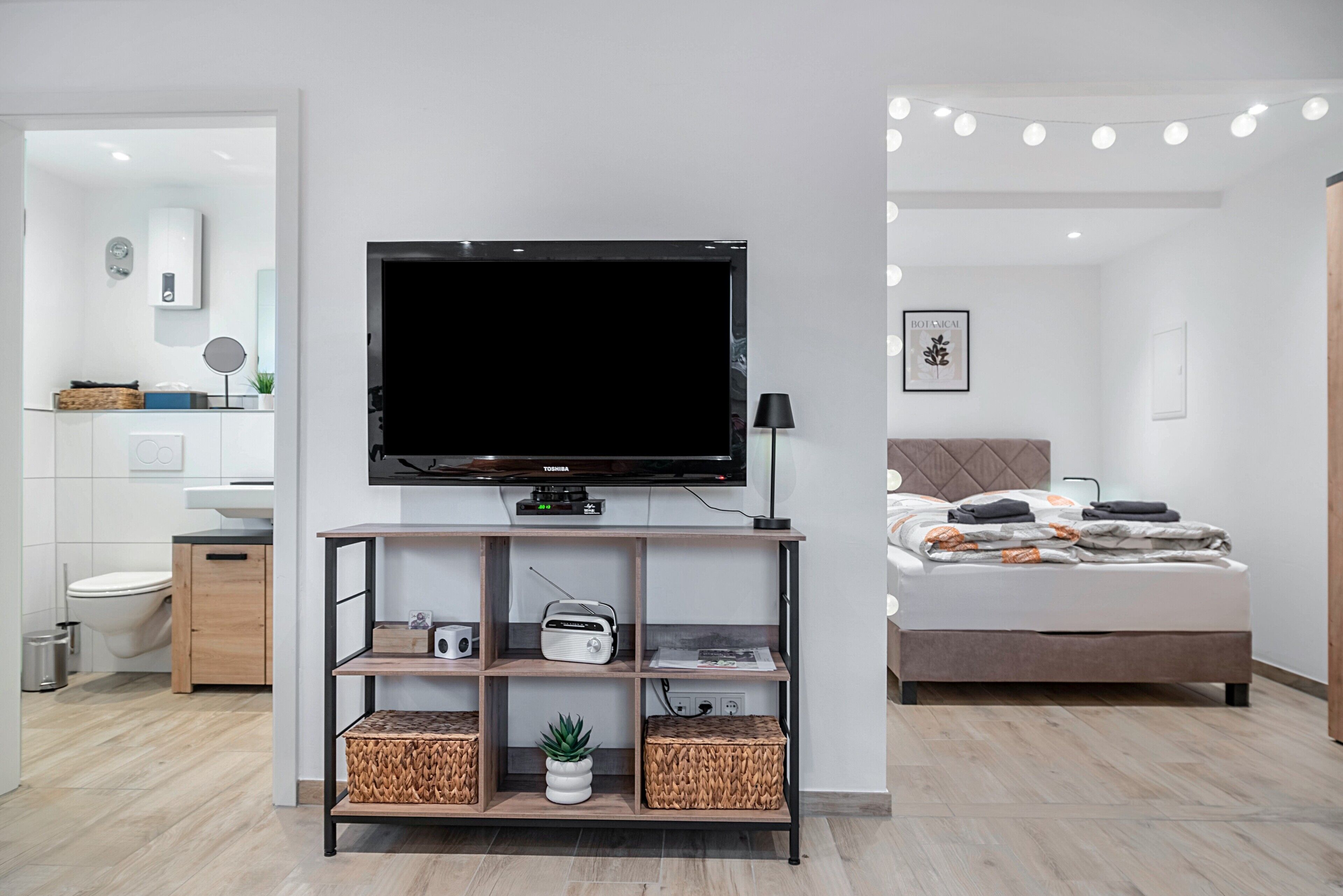 Een moderne hotelkamer met een flatscreen televisie, een nachtkastje, een bed en een badkamer die door een open deur zichtbaar is.