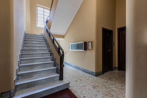 Una scala con corrimano, pavimento piastrellato, una finestra e una porta.