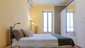 A bedroom with a wooden bed, a bedside table, a lamp, and a window with blinds. - Bramante Enchanting Home by Wonderful Italy (Turin)