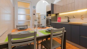 A modern kitchen with grey cabinets, a wooden countertop, and a dining area with a table set for two. - Bramante Enchanting Home by Wonderful Italy (Turin)