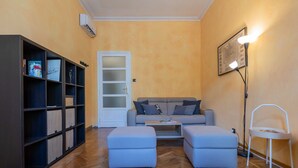 A living room with a sofa, ottomans, a bookshelf, a door, and a floor lamp. - Bramante Enchanting Home by Wonderful Italy (Turin)