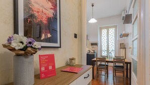 A hotel room with a wooden counter, a framed cityscape artwork, a welcome sign, and a dining area with a table and chairs. - Bramante Enchanting Home by Wonderful Italy (Turin)