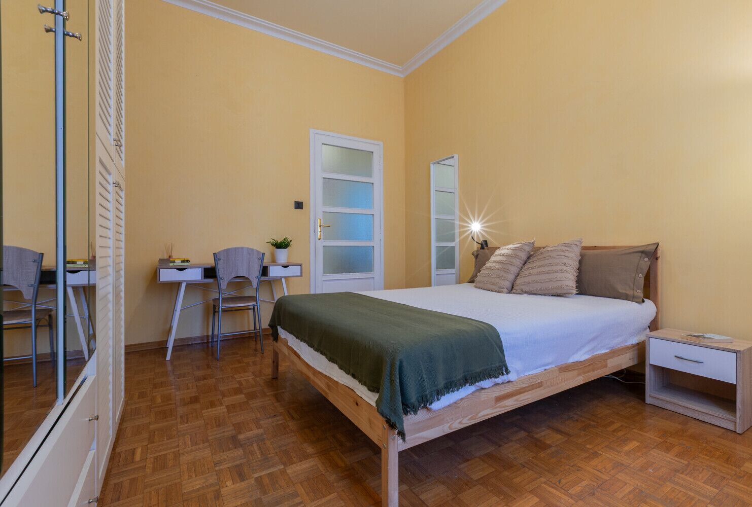 A bedroom with a bed, a desk, and a chair.
