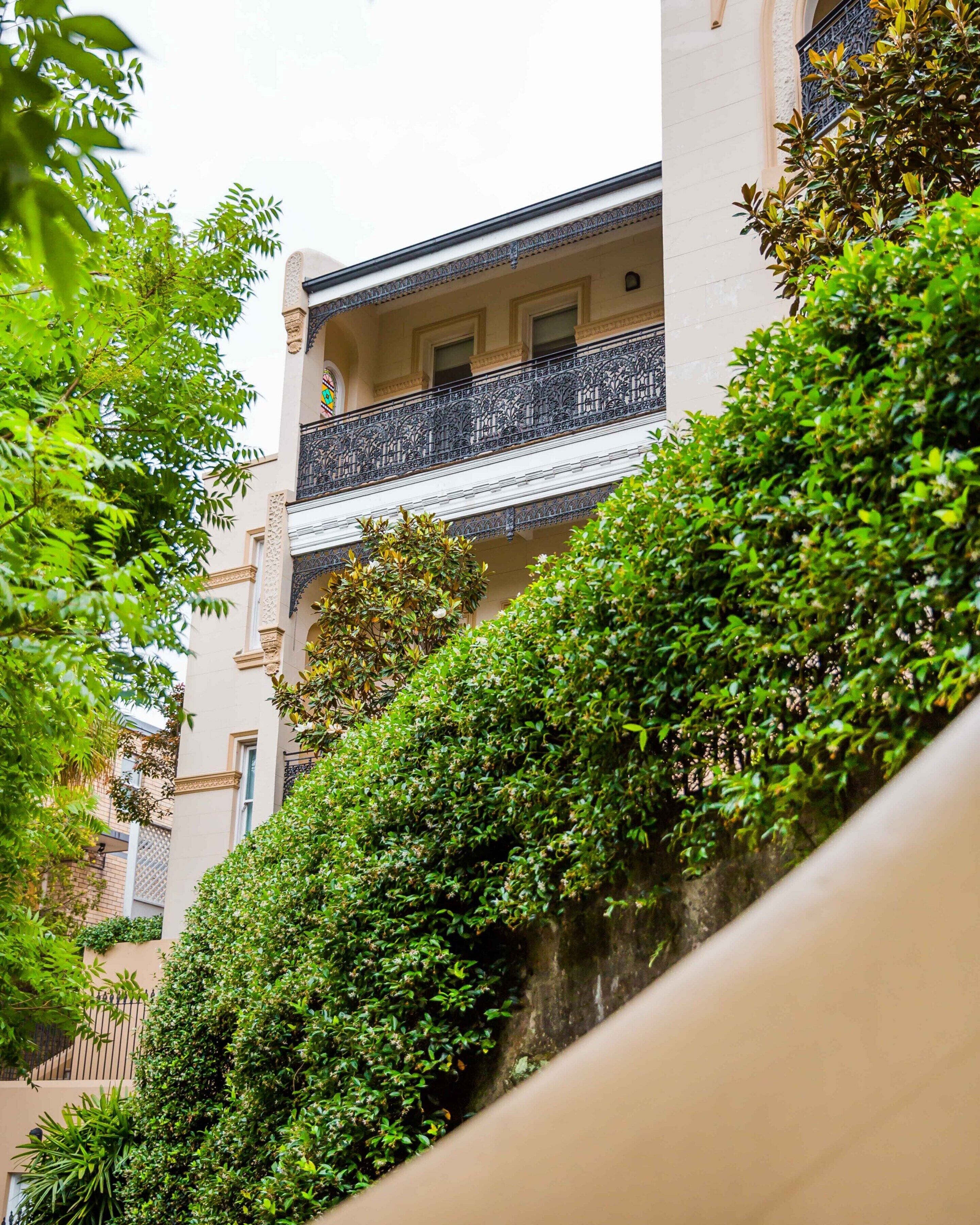 A multi-story building with balconies, surrounded by lush greenery.