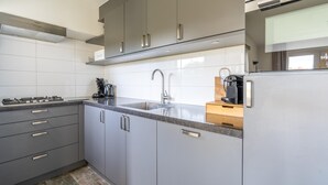 A modern kitchen with grey cabinets, a stainless steel sink, and a built-in oven.