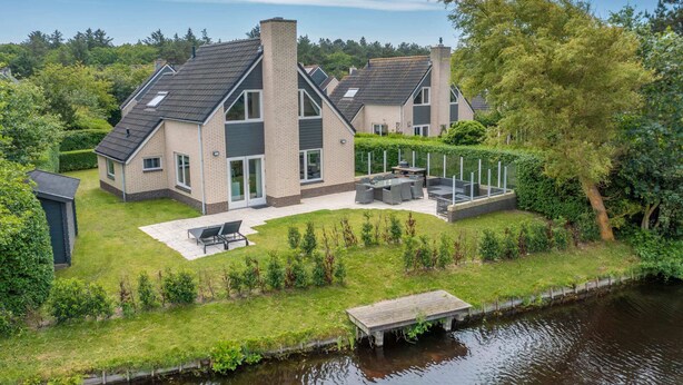 A modern house with a large patio, a swimming pool, and a dock.