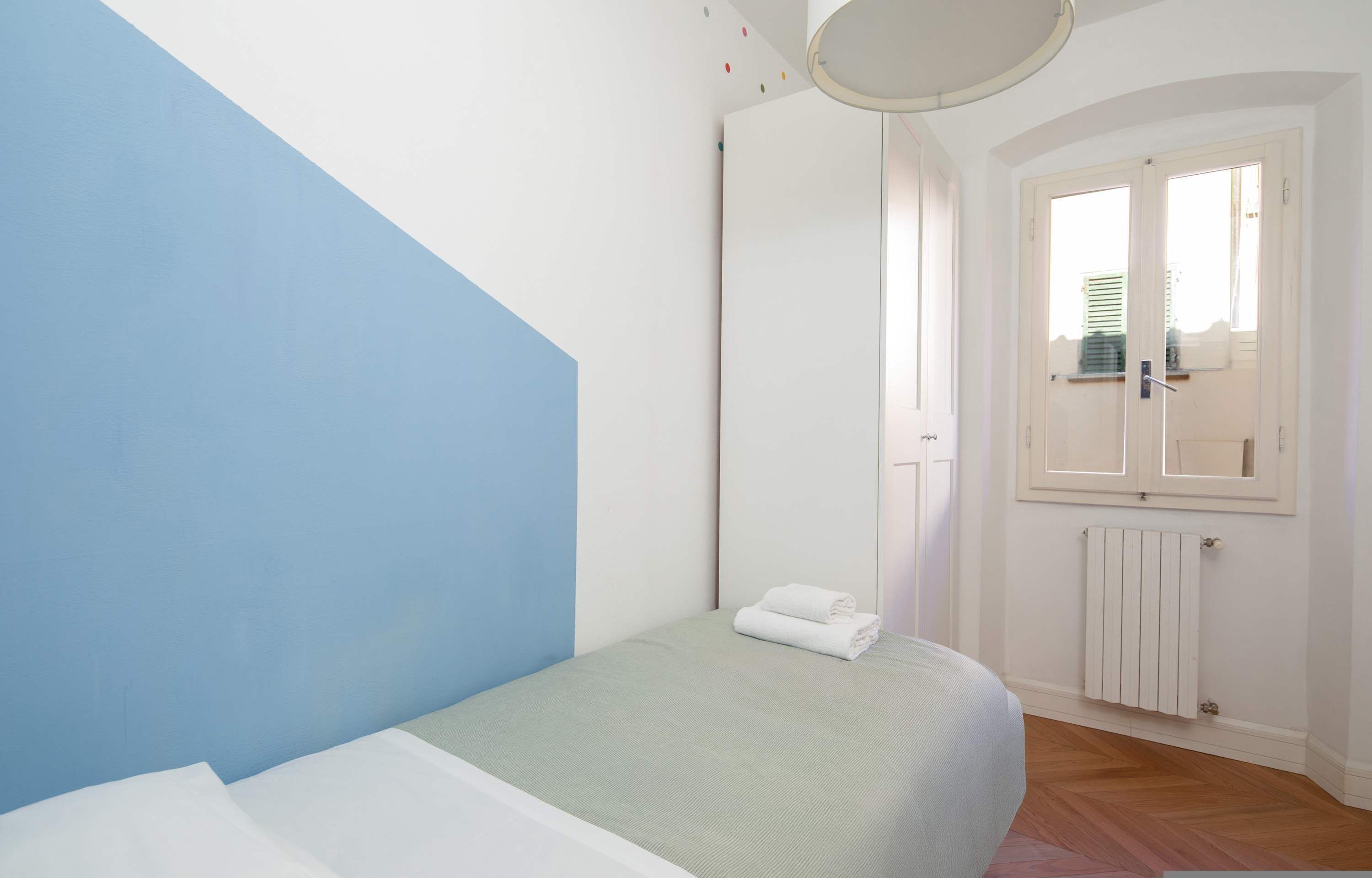 Una camera da letto con un letto, un termosifone e una finestra con persiane.