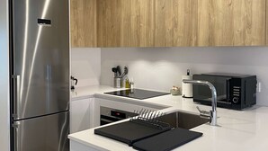 A modern kitchen with a stainless steel refrigerator, a black microwave, and a sink with a sleek faucet. - w Modern 2BR With Terrace in Chueca (Madrid)