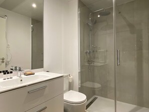 A modern bathroom with a glass-enclosed shower, a white sink with a soap dispenser, and a toilet. - w Modern 2BR With Terrace in Chueca (Madrid)