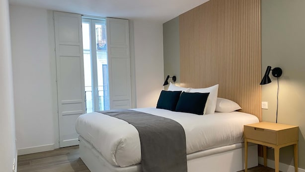 Un dormitorio moderno con cama, mesita de noche y vistas al exterior.