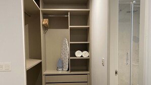 Un vestidor con estantes, una barra para colgar ropa y un centro de planchado integrado.