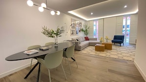 Una sala de estar moderna con comedor, que incluye un sofá, una mesa de centro y una mesa de comedor con sillas.