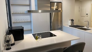 Una cocina moderna con un refrigerador de acero inoxidable, horno empotrado y encimera blanca.