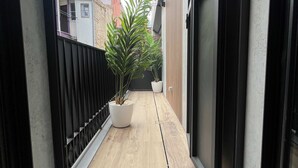 A narrow corridor with a wooden floor, a black metal fence on one side, and a potted plant in the center. - w Impressive 3BR w Sunny Terrace in Chueca (Madrid)