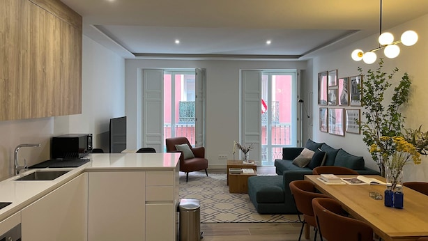 A modern kitchen with a built-in microwave, a dining area with a wooden table and chairs, and a living room with a sofa and a coffee table. - w Impressive 3BR w Sunny Terrace in Chueca (Madrid)