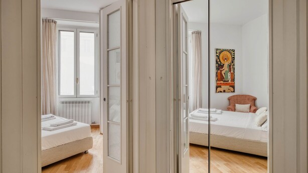 Un dormitorio con dos camas, un radiador y una ventana con cortinas.