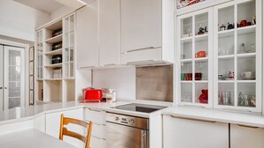 Una cocina moderna con armarios blancos, lavavajillas de acero inoxidable y un tostador rojo.
