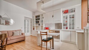 Una cocina moderna con armarios blancos, una mesa de comedor con sillas y un electrodoméstico rojo.