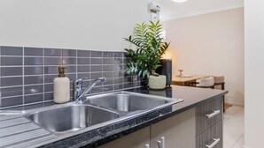 Une cuisine moderne avec un évier à deux bacs, une plante et une petite table avec des chaises.