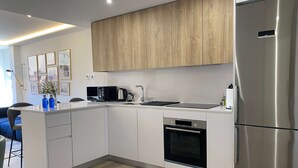 Una cucina moderna con mobili bianchi, un frigorifero in acciaio inossidabile, un forno a microonde e un forno.