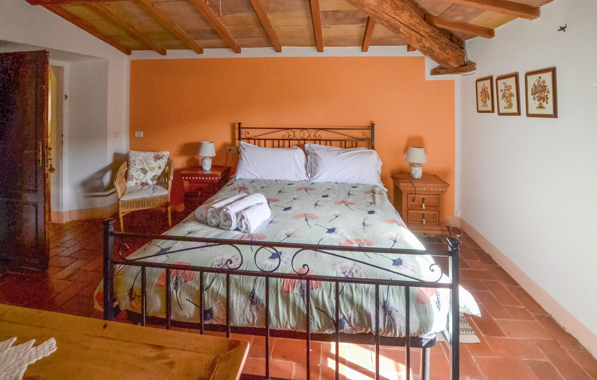 A bedroom with a bed, two bedside tables with lamps, a chair, and a wooden bench.