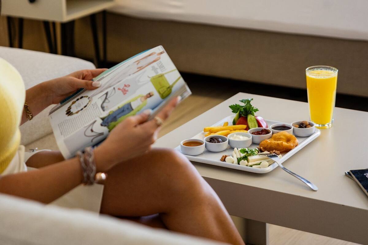 A hotel room with a bed, bedside table, and a breakfast tray with food and drinks.