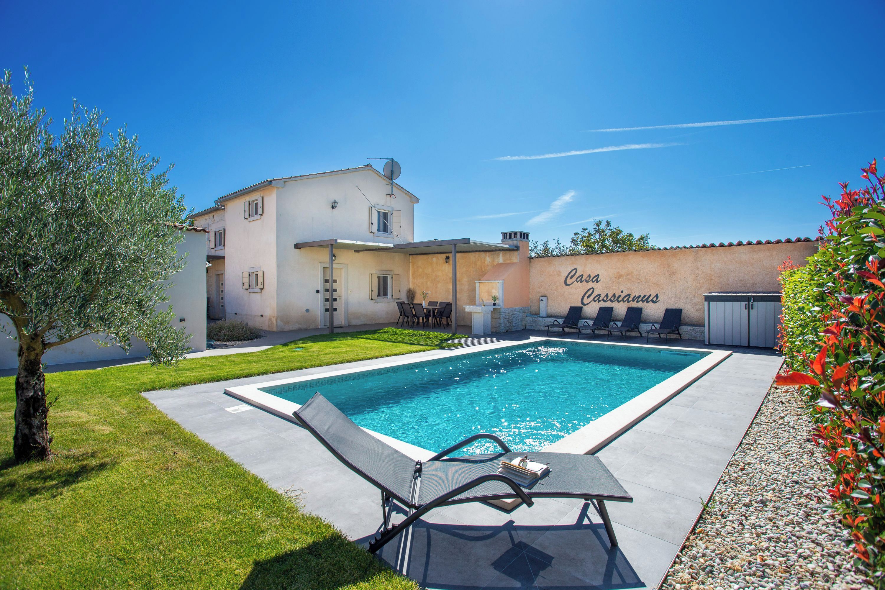 A swimming pool with lounge chairs, a table, and a building with a sign reading "Casa Cassandras."