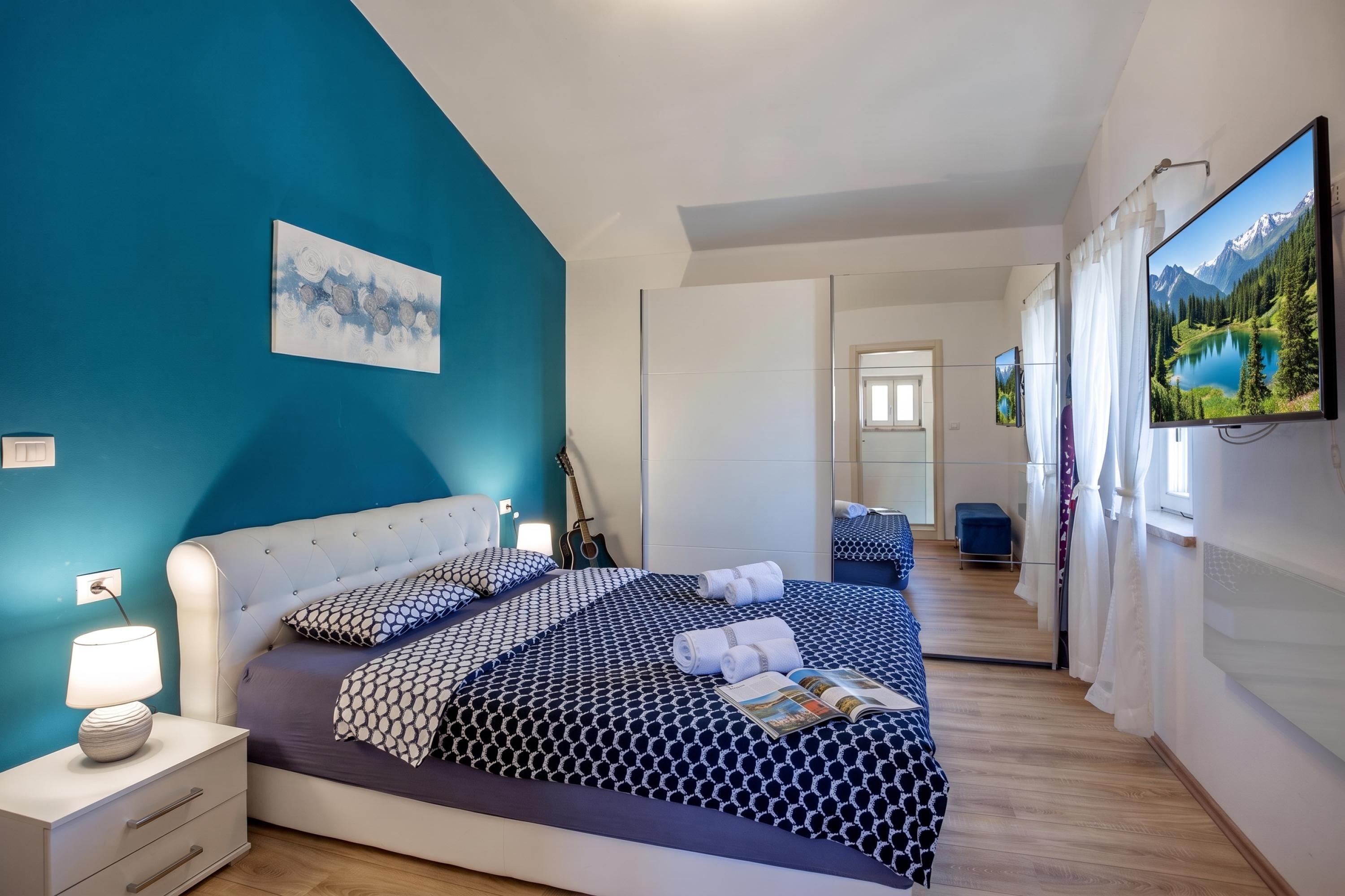 Quarto moderno com uma cama grande, um violão e uma pintura na parede.