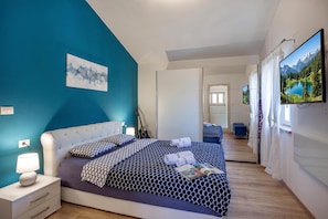 A modern bedroom with a large bed, a guitar, and a painting on the wall.