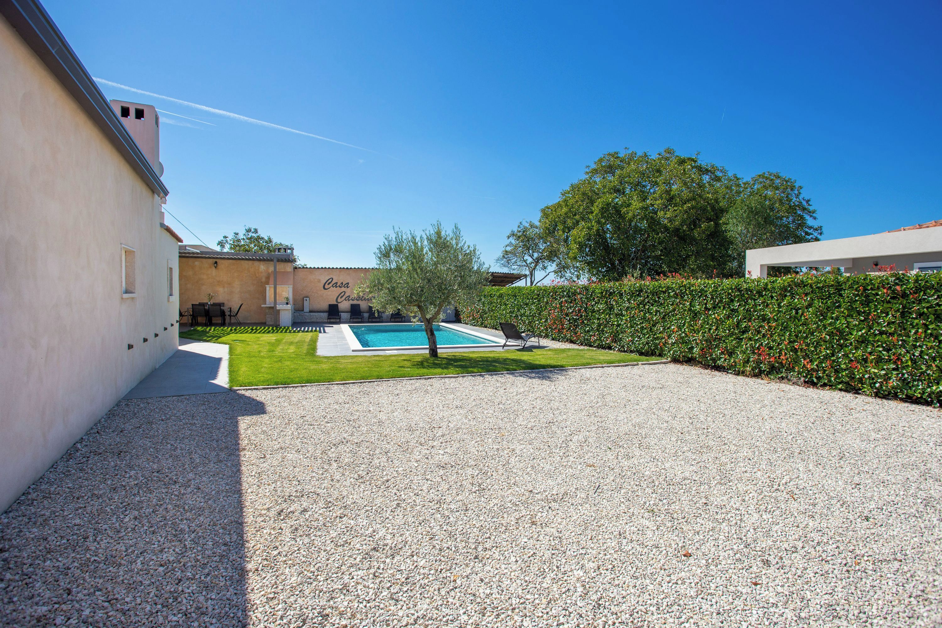 Una casa moderna con piscina, césped cuidado y entrada de grava.