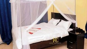 A bed with a white canopy, a bedside table, and a black nightstand.