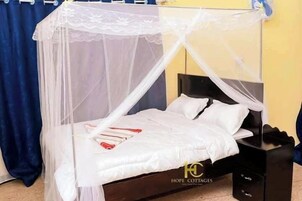 Una cama con dosel blanco, una mesita de noche y un buró negro.